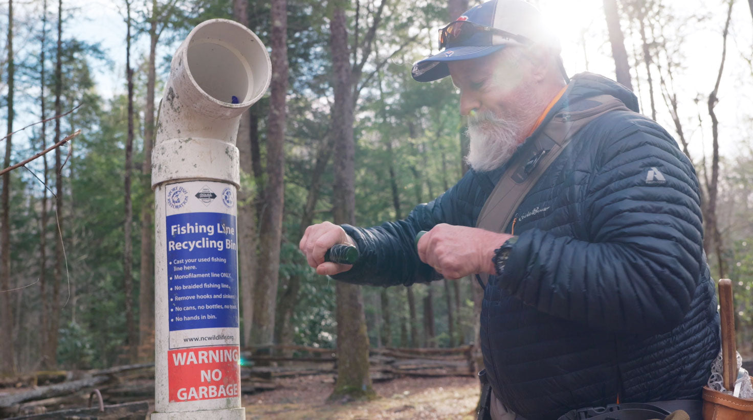 Angler using the Leader Eater Mini to deposit fishing line into a fishing line recycling bin in the field
